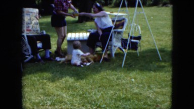 1951: a family with a baby sitting on the lawn outdoor in the shade CLEVELAND