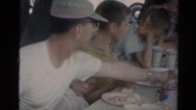 1964: people sitting casually at a picnic table in a park eating lunch