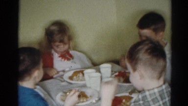 1964: four children are eating dinner together at their own table with plates