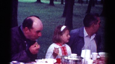 1964: young girl sitting between two male relatives at picnic table CALIFORNIA