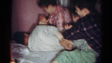 1964: several kids in pajamas jumping into bed with dad and attacking him