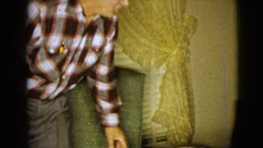 1968: elderly man getting out of his chair and joining a woman on a couch