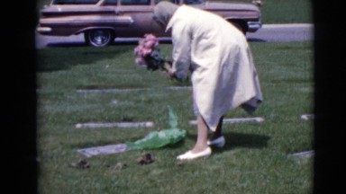 1968: a woman at a grave site putting pink flowers on the grave. CLARKSDALE
