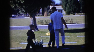 1968: father speaking to two sons in graveyard by gravesite CLARKSDALE, ARIZONA