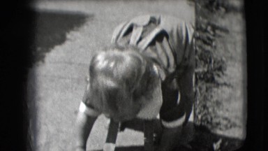1942: Toddler in Overalls Stumbles on Sidewalk as Two Men Walk By New York