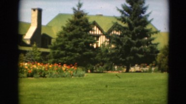 1949: a vast edificacion with green roofs is surrounded by lots of vegetation
