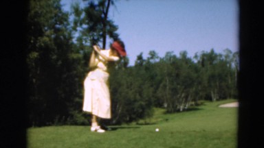 1949: a woman in a dress on a golf course hitting a golf ball MINNESOTA