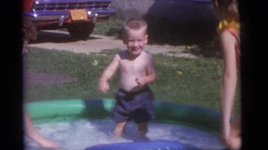 1965: Mother and Children Splashing in Small Wading Pool in Yard, Camden