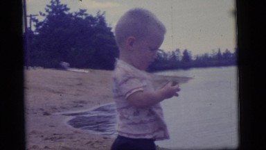 1965: a young male toddler finds a small rock on the bank of a river