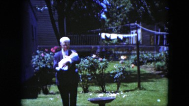1951: older man holding baby and walking toward camera while smiling CLEVELAND