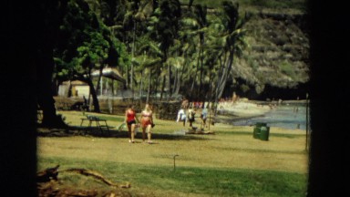 1966: two women walking holding hands along a grassy area near the coast HAWAII