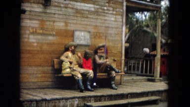 1967: a little girl examines cowboy statues on a bench DISNEYLAND, CALIFORNIA