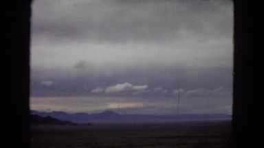 1967: image from a moving car of scenery, hills, mountains, signs, and sky
