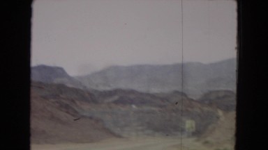 1967: a car driving down the highway with rugged , rocky mountains