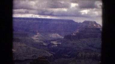 1967: a beautiful view of the rugged grand canyon under a dark, cloudy sky