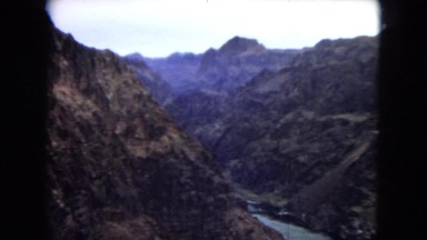 1967: panoramic view of a canyon with a blue river leading to a man-made dam