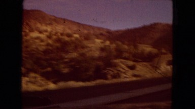 1967: view of a mountainside and a road from a moving car with blue sky