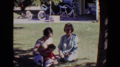 1967: a family, including children, outdoor in the shade sitting on the lawn