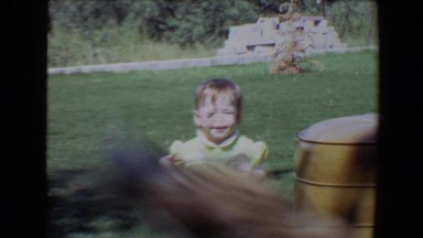 1967: a dog outdoor, running away from a baby sitting in the grass TUCSON