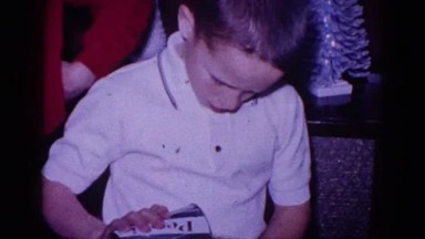1968: a young boy pouring a soda into a cup as another boy makes rabbit ears