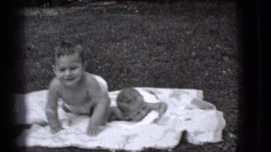 1941: children laying on blankets a toddler tries to comfort his infant brother