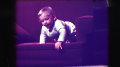 1942: blonde haired toddler climbs down from a couch and bumps his head.