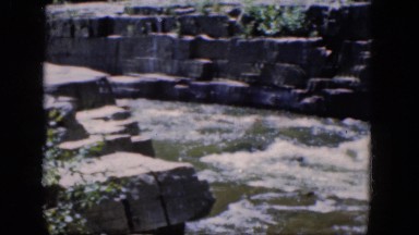 1964: a roaring river flows between rocks topped with grass and trees