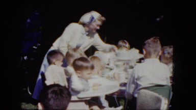 1964: a woman helping the children that are sitting at the table. NIAGARA FALLS
