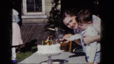 1964: woman cutting birthday cake with child at a party NIAGARA FALLS, ONTARIO