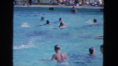 1965: a bunch of children playing and splashing in a large swimming pool