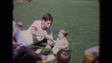 1967: a baby and family seated outdoor on the grass playing in the sun TUCSON