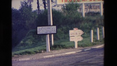 1969: cars pass each other at a cross road marked with several signs to guide