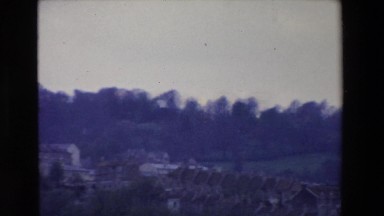 1969: city with dozens of row houses with open fields and trees in background
