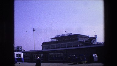 1967: passengers carrying luggage nearing buses in the terminal AMSTERDAM