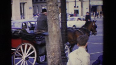1969: Horse-Drawn Carriage Driver on Busy Street in Lourdes, France