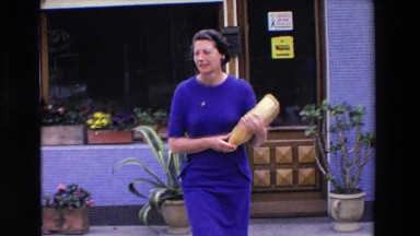 1969: woman walking dressed bread carrying road street LOURDES, FRANCE