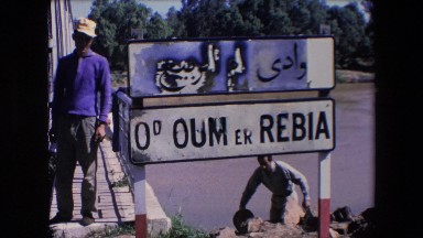 1971: Man Climbing Stairs Near Sign Carrying Hat and Bag