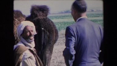 1971: middle eastern man talking to a man in a suit in front of a camel ALGERIA