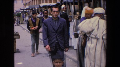 1971: many villagers in a middle eastern marketplace are walking, shopping
