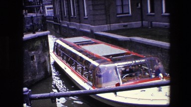 1967: traveling people boat water thru city AMSTERDAM, NETHERLANDS