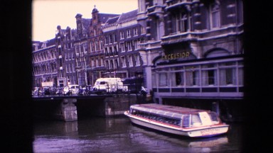1967: a long boat on the water in a beautiful, scenic european city AMSTERDAM