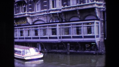 1967: a view of a waterfront hotel with a boat parked in front and a chef