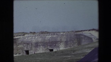 1967: a view of a quarry with door shaped openings in the side of a mountain