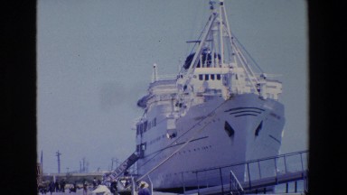 1967: a large white ship is tethered to a dock in a port on a sunny day. PALERMO