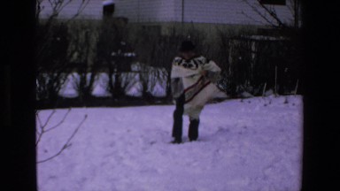 1972: a man wearing a furry poncho is walking on a very snowy ground
