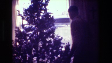 1981: man decorating christmas tree in front of window HOLLYWOOD CALIFORNIA