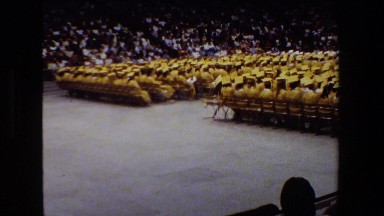 1981: graduates dressed in yellow robes sit in chairs on the floor
