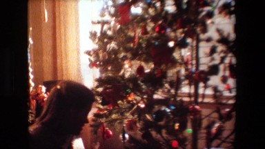 1981: a couple mending a beautifully decorated christmas tree near a window