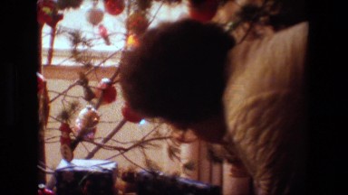 1981: an old lady wearing specs stand near to a decorated christmas tree LANSING