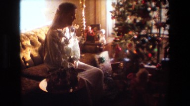 1981: a woman in a white nightgown looking at christmas presents under the tree